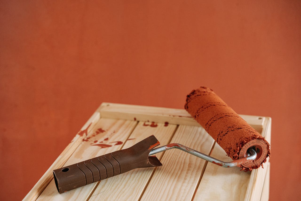 Paint roller resting on a tray with fresh terracotta-coloured paint