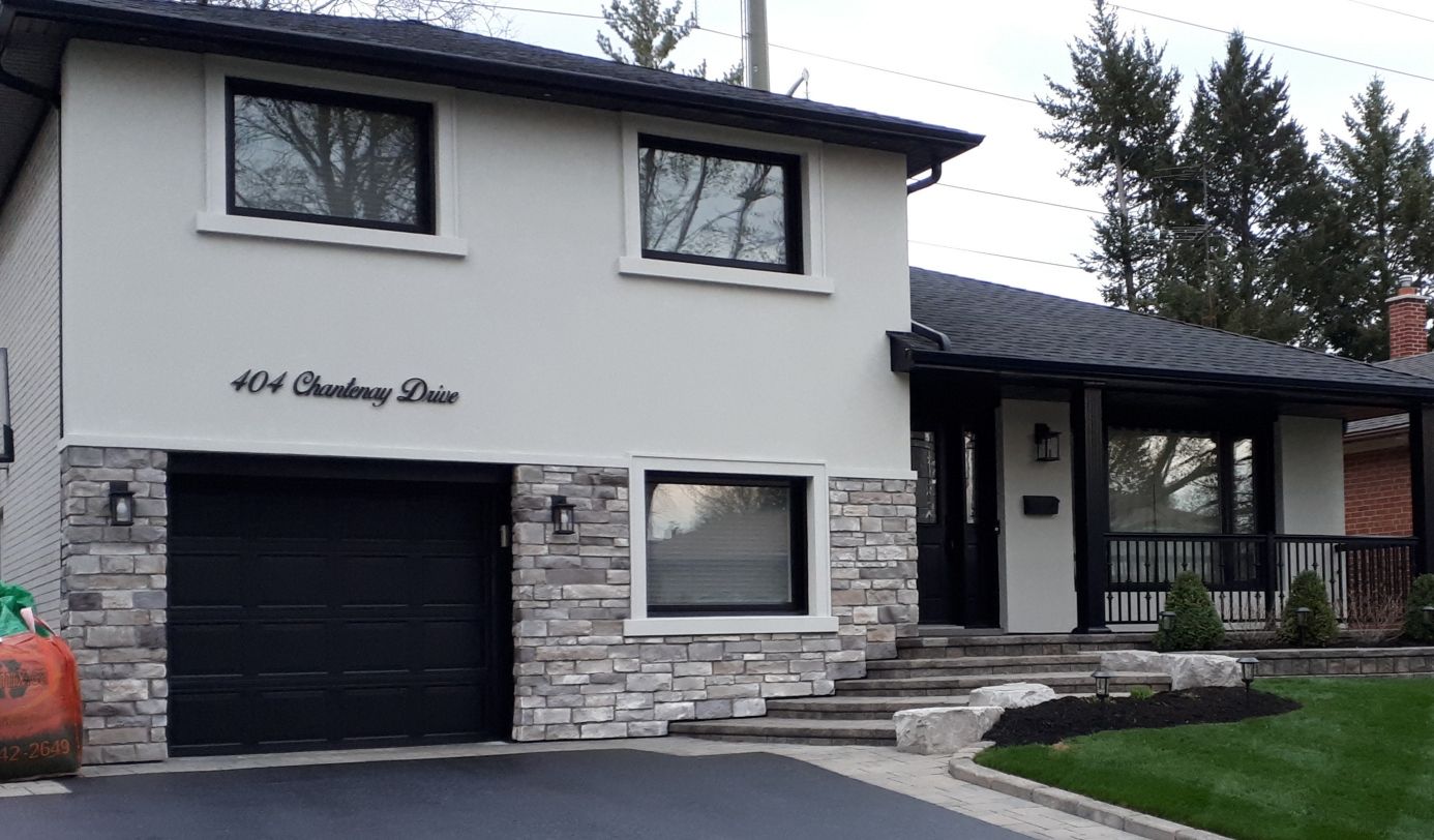Two-storey home with a light stucco finish and stone veneer around the garage