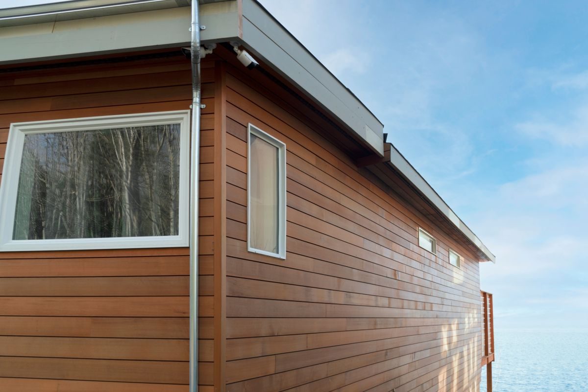 Wood-sided house wall with large windows in bright afternoon sun