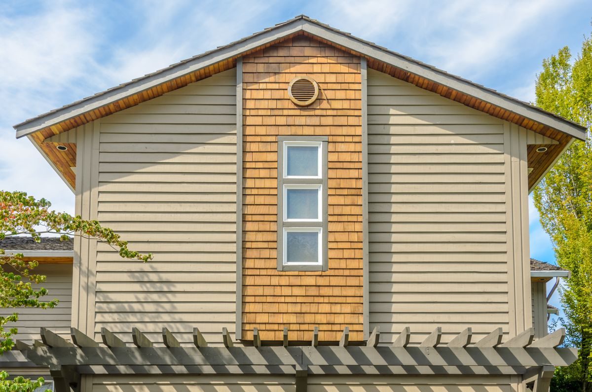 Gable end of a two-storey home with lap siding, a shingle-style accent and white window trim