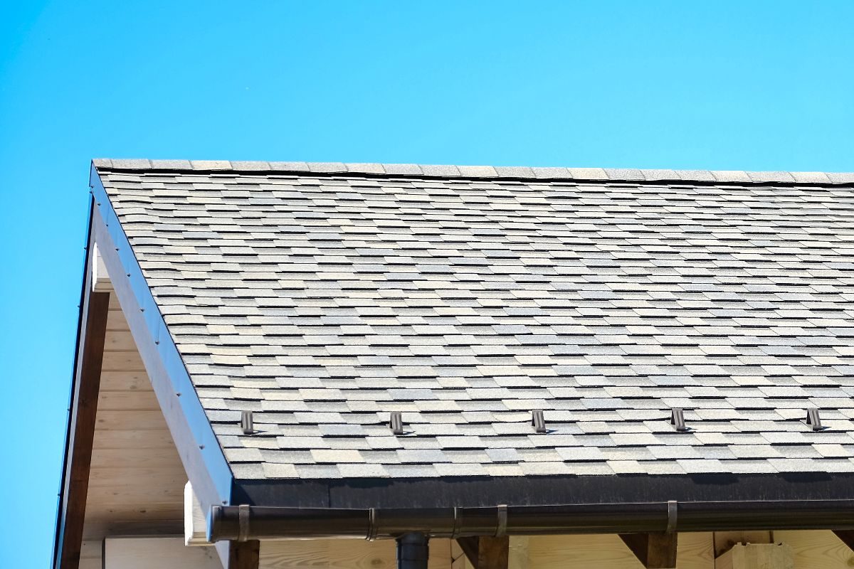 Roof edge with light grey shingles, aluminum eavestrough and soffit