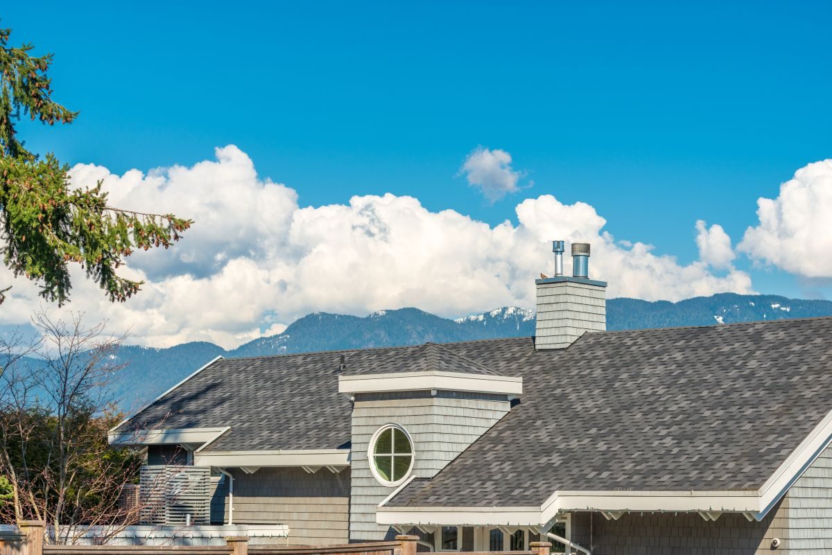 Grey shingled roof and eaves of a home with mountains on the horizon