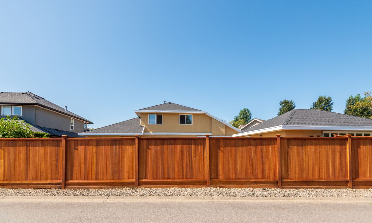 Stained cedar privacy fence with capped posts along a residential back lane